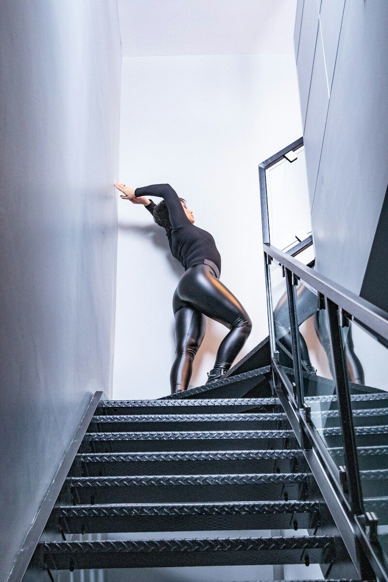 woman in black shirt and black leggings standing on staircase